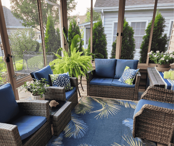 Comfortable screen room porch with wicker seating, blue cushions, and large screened windows for backyard views.