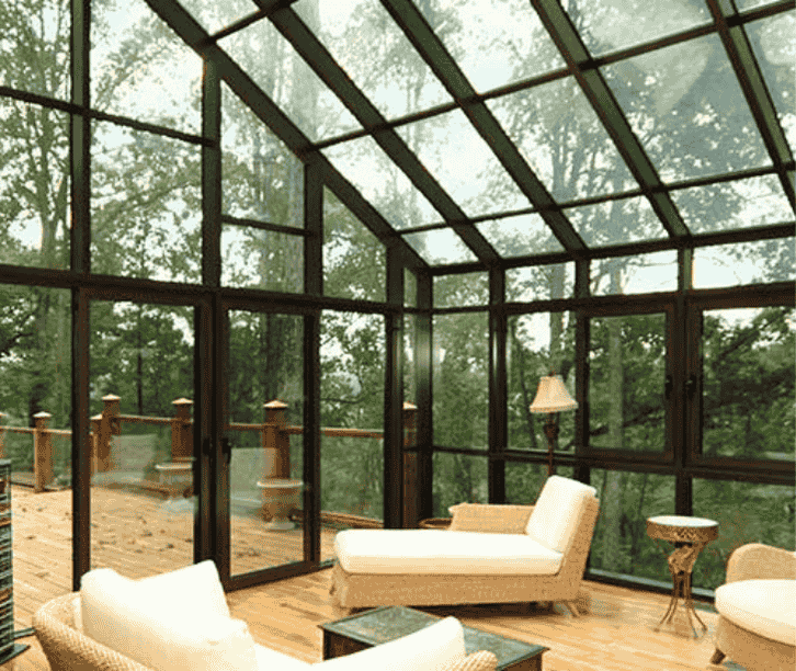 Bright solarium sunroom interior with glass ceiling, panoramic windows, and modern seating overlooking a backyard.