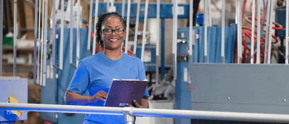 A Great Day Improvements factory worker smiles while checking a clipboard.