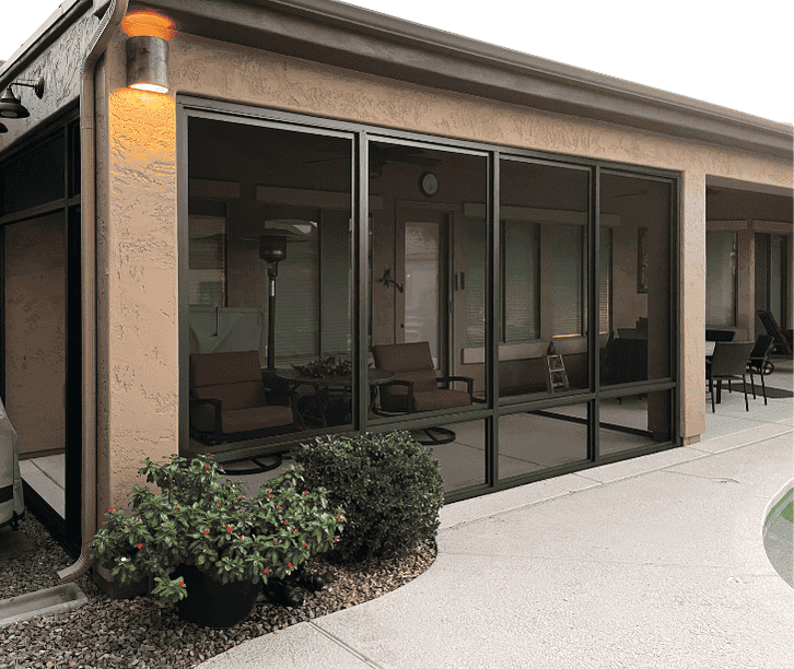 Modern screen room enclosure with dark frames and sliding screen panels attached to a patio beside a swimming pool.