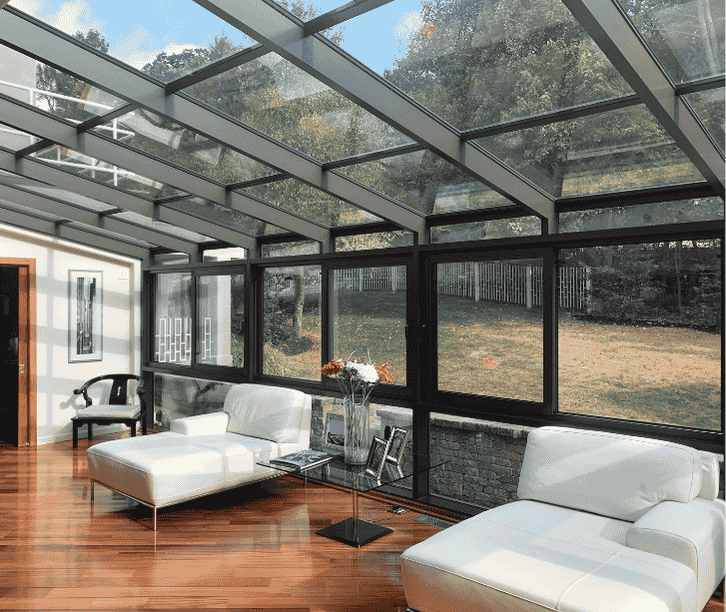 Interior of a glass solarium sunroom addition with full glass roof panels and large windows overlooking a wooded deck.