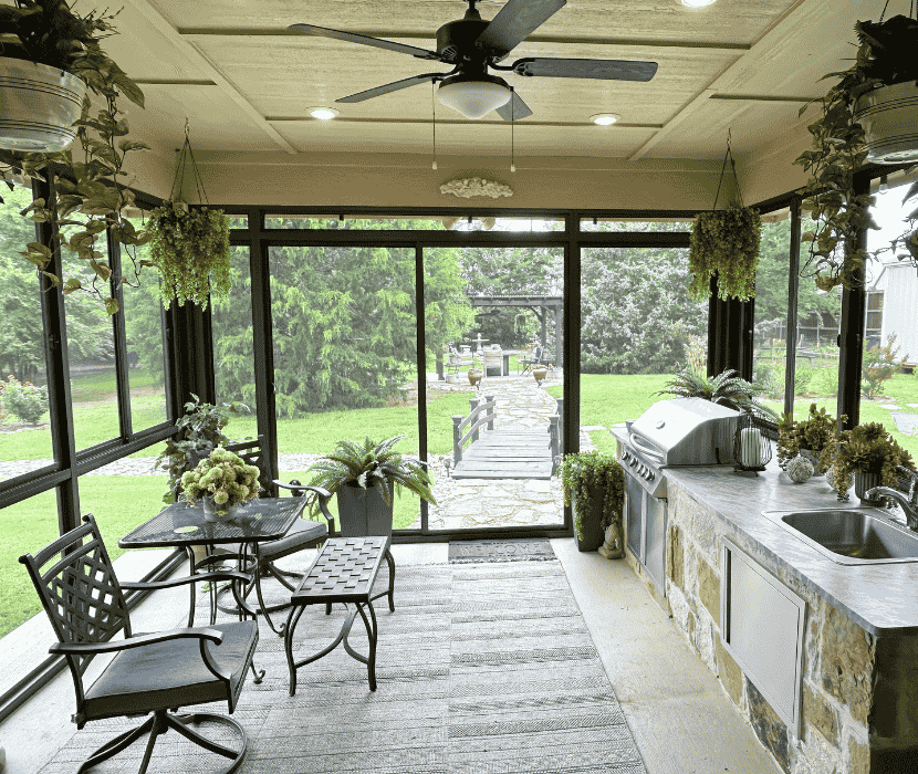 Screen room enclosure with outdoor kitchen, dining area, and large screened windows overlooking a landscaped backyard.