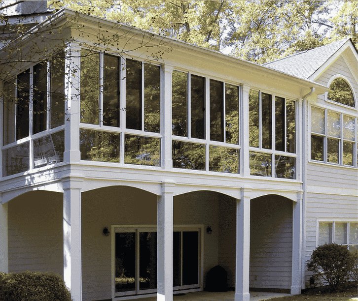 Second story three season sunroom addition with wraparound windows above a covered patio on a white home.