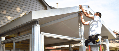 A Great Day Improvements sunroom installer works on the roofline.
