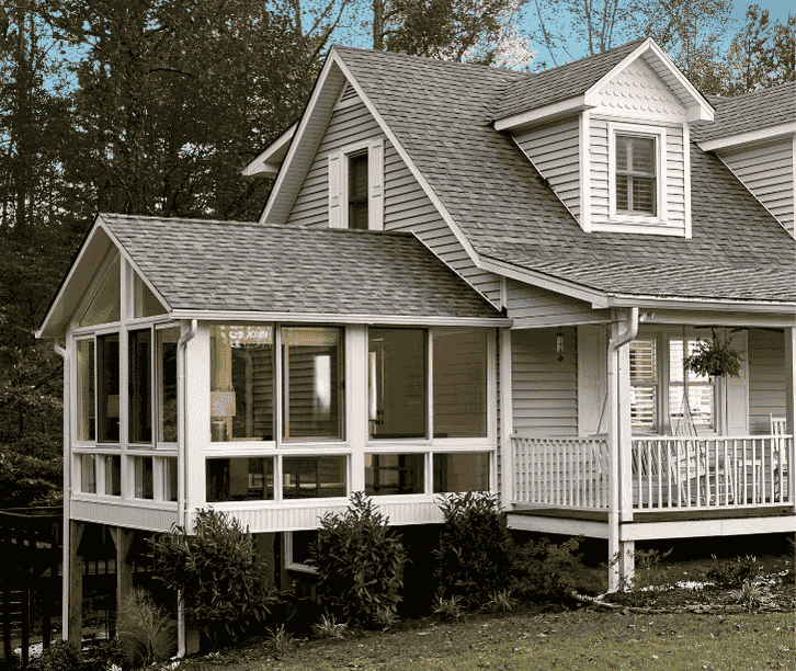 Traditional white four season sunroom enclosure with wraparound windows attached to a classic country style home.