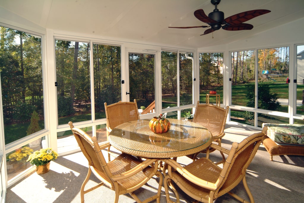 Charlotte sunroom with energy-efficient windows, wicker furniture, ceiling fan, and autumn-themed decor