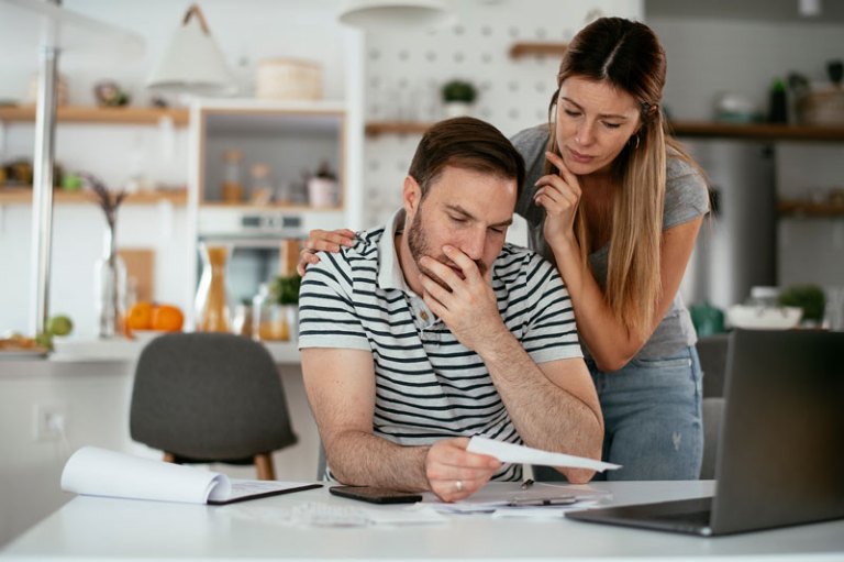A couple looks over some documents and a laptop at their dining table to make some important decisions.