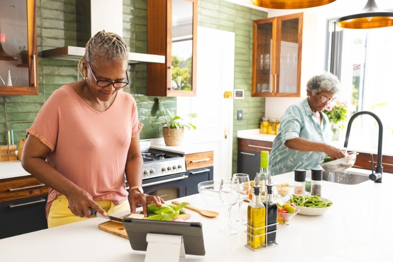 Two senior women prepare a meal in a kitchen made with universal design.
