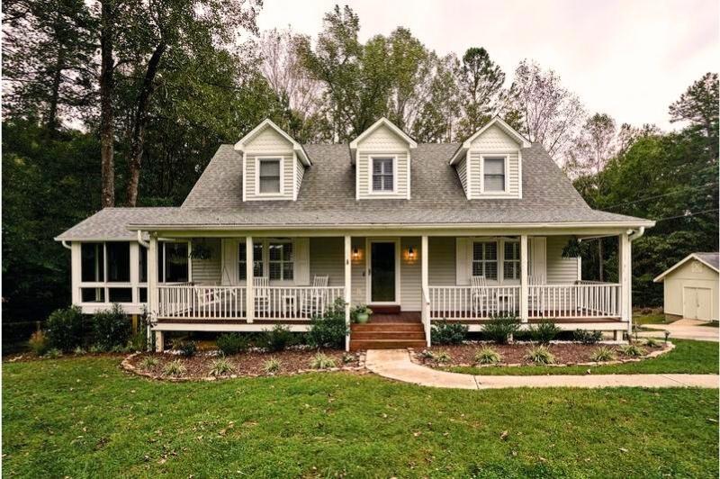 Charming Cape Cod style house with gray siding, gable roof, front porch, dormer windows, and landscaped yard.