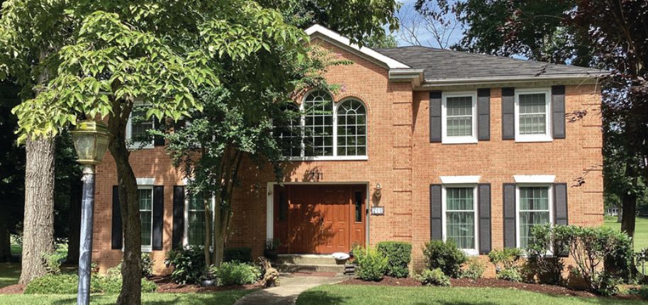 Two-story traditional brick home in Cleveland with black shutters and a landscaped yard—built for long-term durability and stress-free maintenance.
