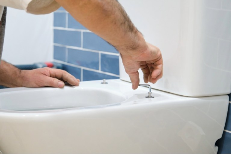 A professional renovator installs a new toilet in a residential bathroom