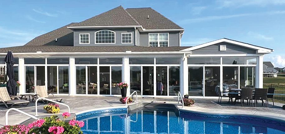 Modern sunroom installation by Great Day Improvements in Apollo Beach, FL, showcasing sleek glass walls and a luxurious backyard pool setup.
