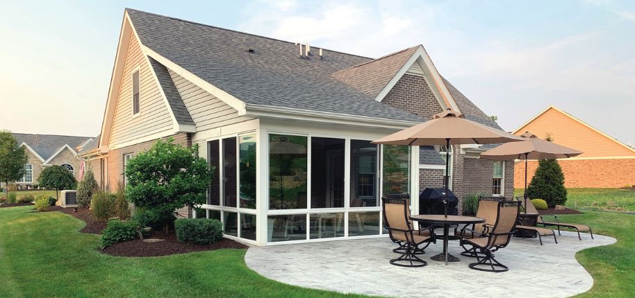 Beautifully remodeled home exterior with enclosed sunroom and stamped concrete patio, completed by Great Day Improvements in Danville.