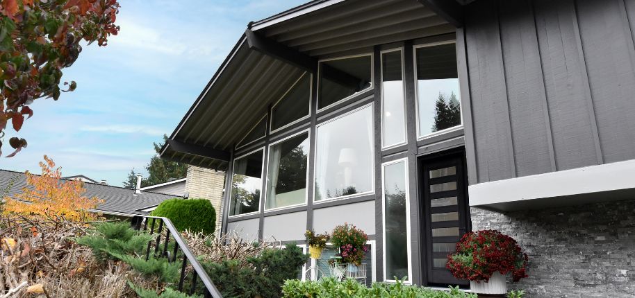 Custom home remodel in Krikland with vertical siding, stone accent, and Northwest-inspired landscaping.
