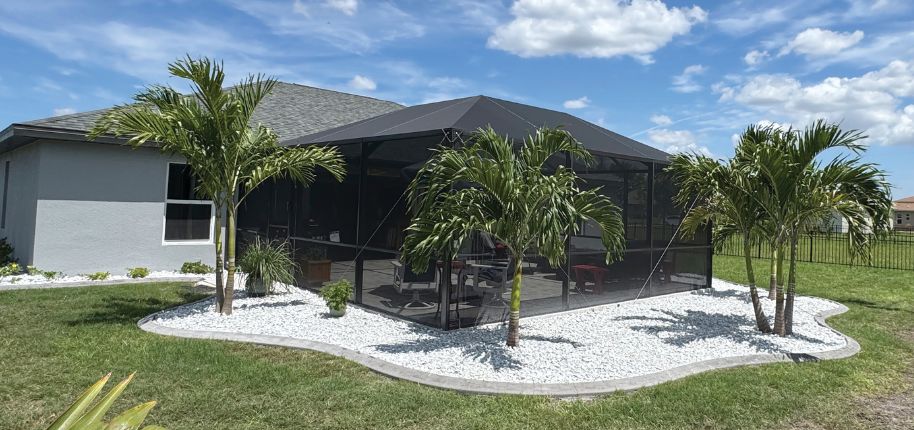 Stylish lanai enclosure in Valrico surrounded by sculpted white stone landscaping and palm trees—perfect for homeowners seeking function and curb appeal with help from Great Day Improvements.