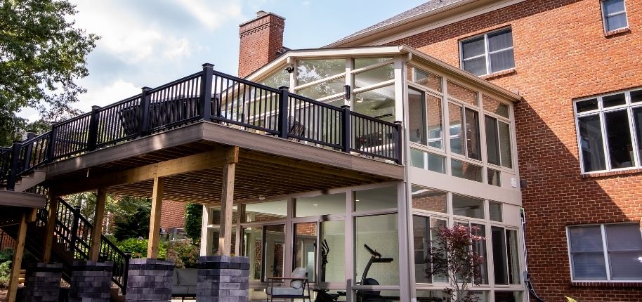 Custom two-story sunroom and elevated deck addition completed by Great Day Improvements, seamlessly expanding this brick home’s outdoor living space