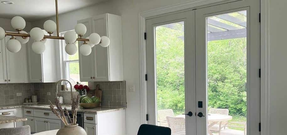 Sun-filled kitchen featuring modern cabinetry, statement lighting, and energy-efficient glass patio doors remodeled by Great Day Improvements to improve comfort, light, and everyday living.