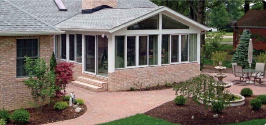 Brick home with a custom sunroom addition and expansive windows, remodeled by Great Day Improvements to create a seamless indoor-outdoor living space for year-round enjoyment.
