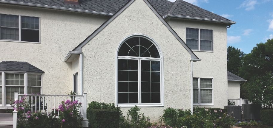 Stucco home featuring a large arched replacement window, remodeled by Great Day Improvements to bring in natural light while enhancing energy efficiency and architectural character.