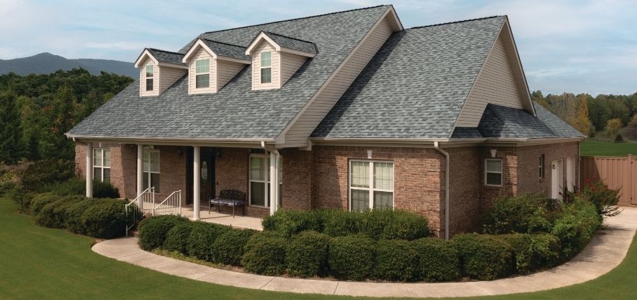 Brick home with new roofing, updated siding accents, and replacement windows, remodeled by Great Day Improvements to improve energy efficiency and timeless exterior style.