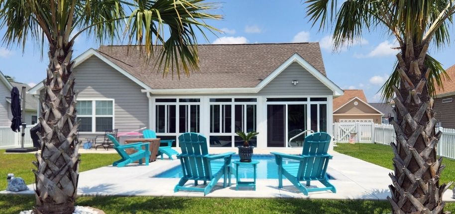 Backyard view of a home with a custom screened enclosure and patio seating, remodeled by Great Day Improvements to extend outdoor living while maintaining comfort and protection.