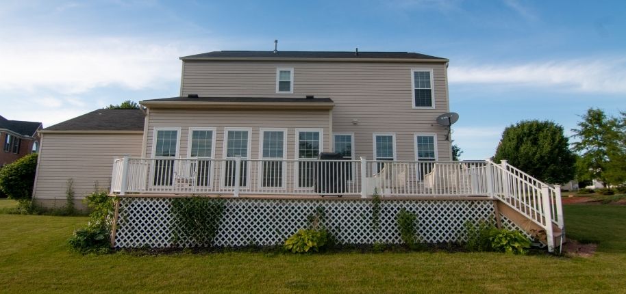 Two-story home with a full-width elevated deck, updated railing, and replacement windows, remodeled by Great Day Improvements to expand outdoor entertaining space and improve functionality.