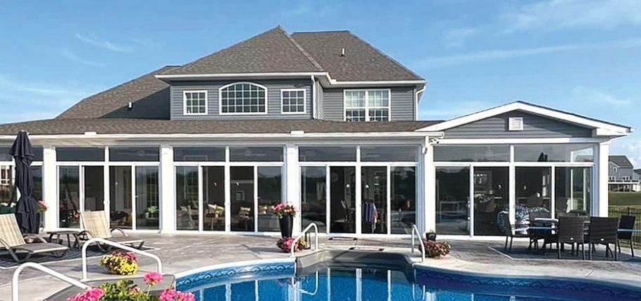 Large home with a custom sunroom addition overlooking a pool, featuring expansive glass walls, remodeled by Great Day Improvements to create a resort-style living experience.