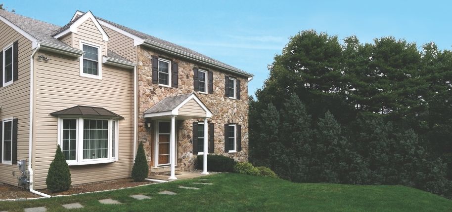 Stone-and-siding home with updated exterior finishes and replacement windows, remodeled by Great Day Improvements to enhance durability, energy efficiency, and classic style.