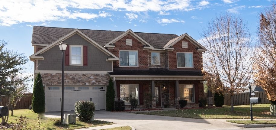 Two-story home with mixed brick and siding exterior, updated garage doors, and replacement windows, remodeled by Great Day Improvements to boost curb appeal and everyday functionality.