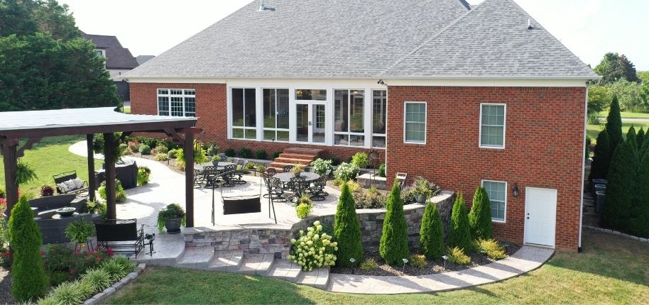 Brick home with a custom patio, pergola, and landscaped outdoor living area, remodeled by Great Day Improvements to create a functional, inviting space for entertaining and relaxation.