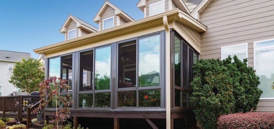 Two-story home with a custom elevated sunroom featuring expansive glass panels, remodeled by Great Day Improvements to add year-round living space and outdoor connection.