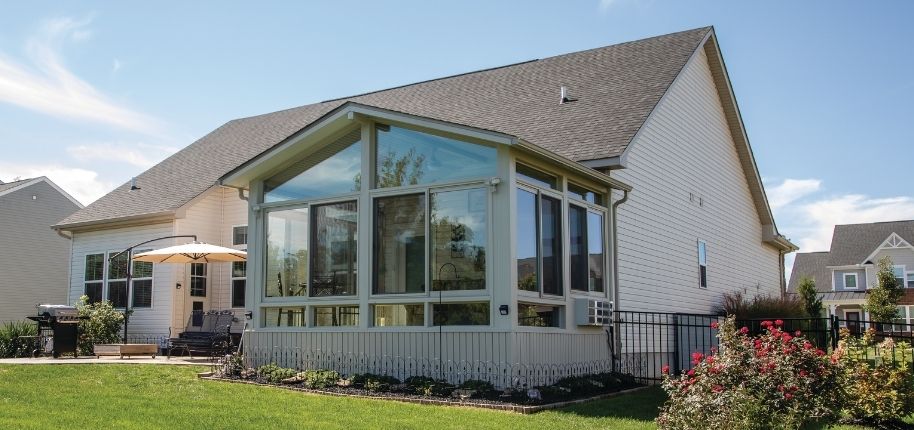 Suburban home with a custom glass sunroom addition and landscaped yard, remodeled by Great Day Improvements to expand living space and improve backyard enjoyment.