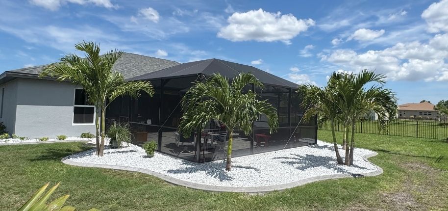 Backyard pool area with a full screened enclosure and tropical landscaping, remodeled by Great Day Improvements to provide protected outdoor living and year-round enjoyment.