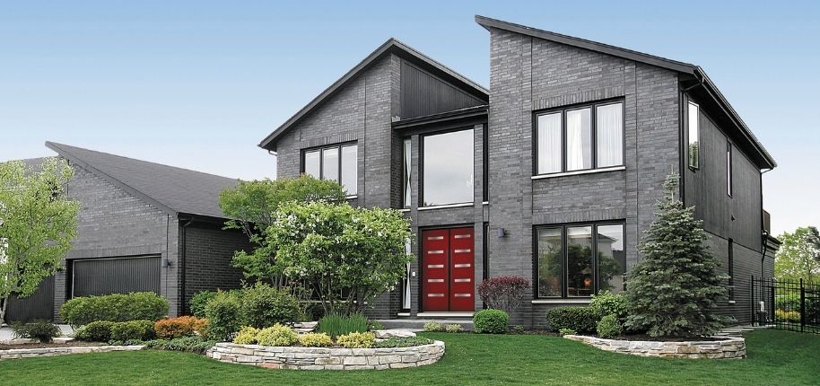 Modern brick home with bold red front doors, updated windows, and clean architectural lines, remodeled by Great Day Improvements to elevate curb appeal and contemporary style.
