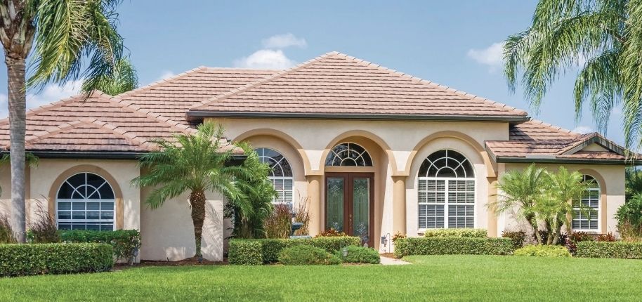 Single-story home with arched windows, updated exterior finishes, and lush landscaping, remodeled by Great Day Improvements to enhance curb appeal and energy efficiency.