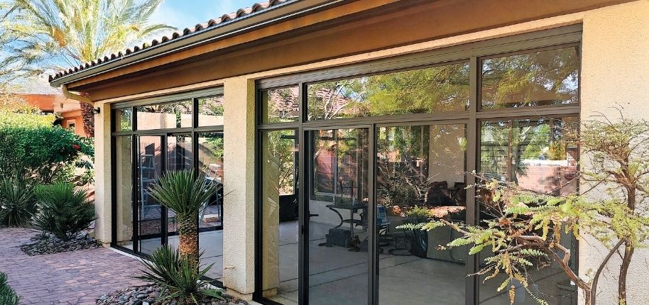 Southwest-style home with custom glass sunroom enclosure and expansive sliding doors, remodeled by Great Day Improvements to blend indoor comfort with outdoor living.