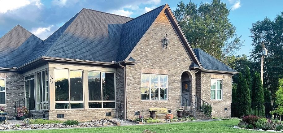 Brick home with a custom sunroom addition and energy-efficient windows, remodeled by Great Day Improvements to add natural light and functional living space.