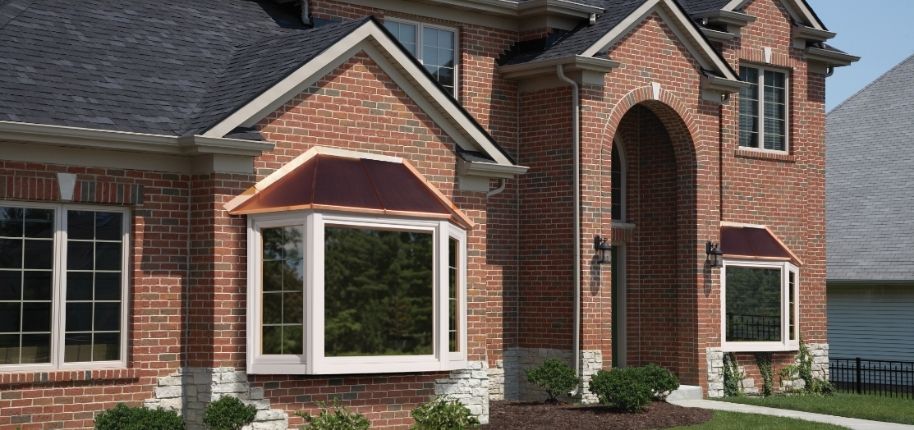 Brick home with a custom bay window and copper roof detail, remodeled by Great Day Improvements to enhance architectural character and energy efficiency.