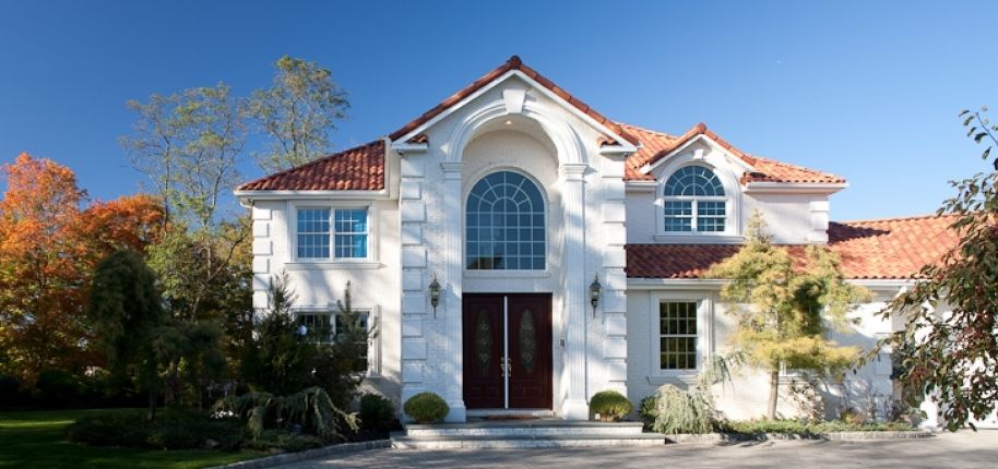 Elegant stucco home with arched windows and updated exterior finishes, remodeled by Great Day Improvements to improve comfort, style, and durability.