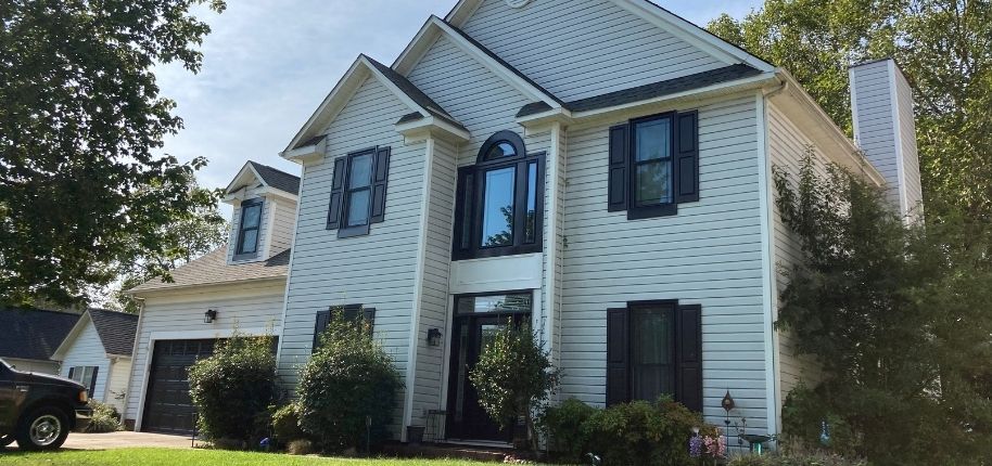 Two-story home with updated siding, black shutters, and a refreshed front entry, remodeled by Great Day Improvements to enhance curb appeal, energy efficiency, and long-term performance.