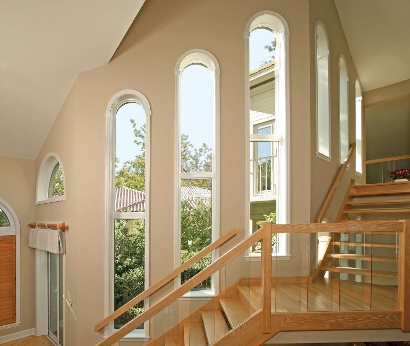Interior view of tall vertical windows along a staircase, providing natural light and a sleek design. An expert home window installation from Great Day Improvements.
