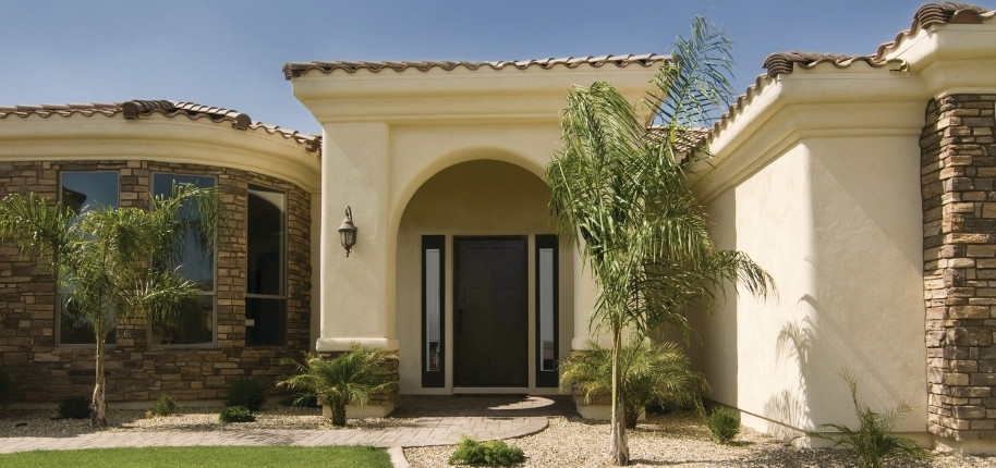 Mediterranean-style stucco home with stone accents and grand arched entry, renovated by Great Day Improvements for a bold, elegant exterior transformation.