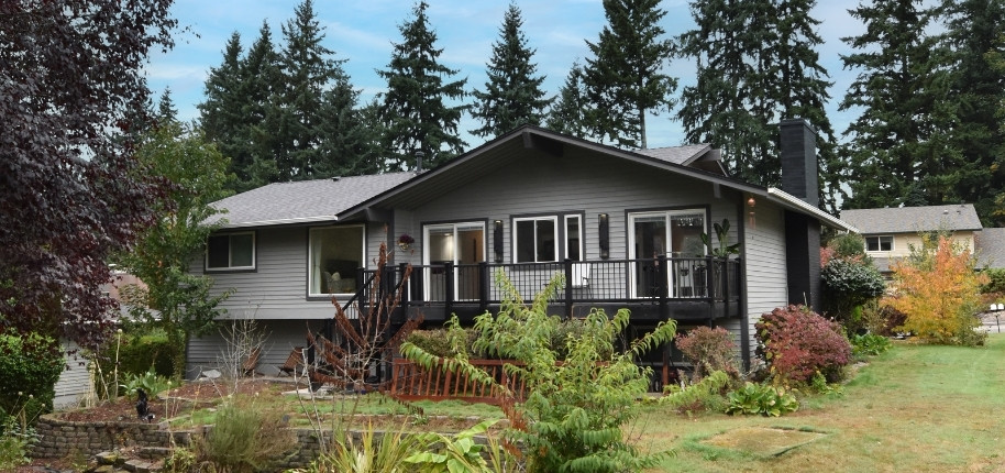 Gray split-level home with updated siding and modern black deck railing, renovated by Great Day Improvements for improved durability and curb appeal.