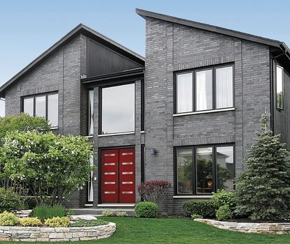 This striking red front door was installed by Great Day Improvements to complement the modern style of this gray brick home.