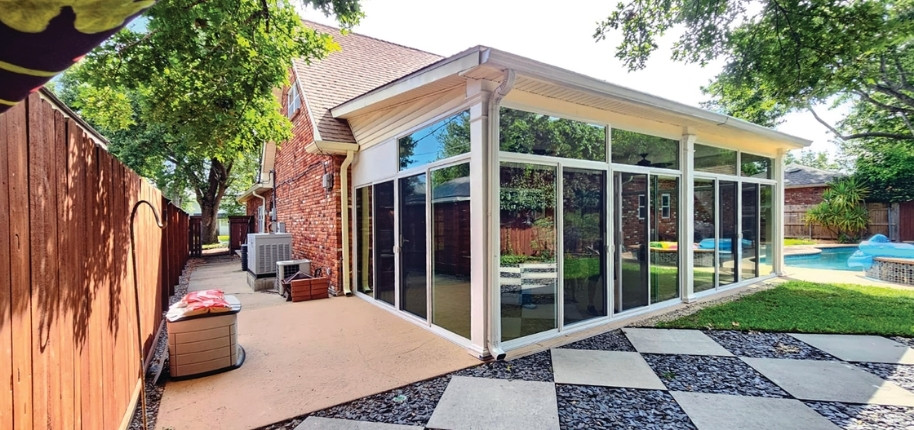 Brick home with large glass sunroom addition overlooking backyard pool, renovated by Great Day Improvements for durable, light-filled living space.