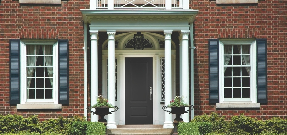 Traditional brick home with stately columned entry and new front door installation, renovated by Great Day Improvements to enhance security and timeless curb appeal.