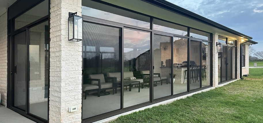 Screened patio enclosure with black aluminum framing and outdoor seating area, renovated by Great Day Improvements for protected, year-round entertaining space.