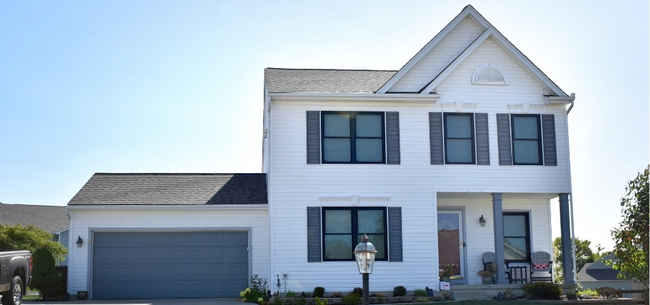 Two-story white siding home with new windows and refreshed trim, renovated by Great Day Improvements to boost energy efficiency and curb appeal.