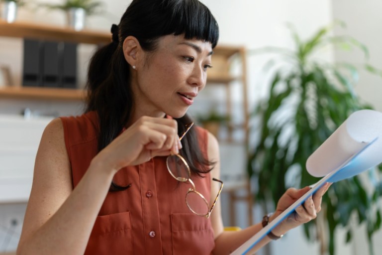 A woman reviews some paperwork in her bright home office.