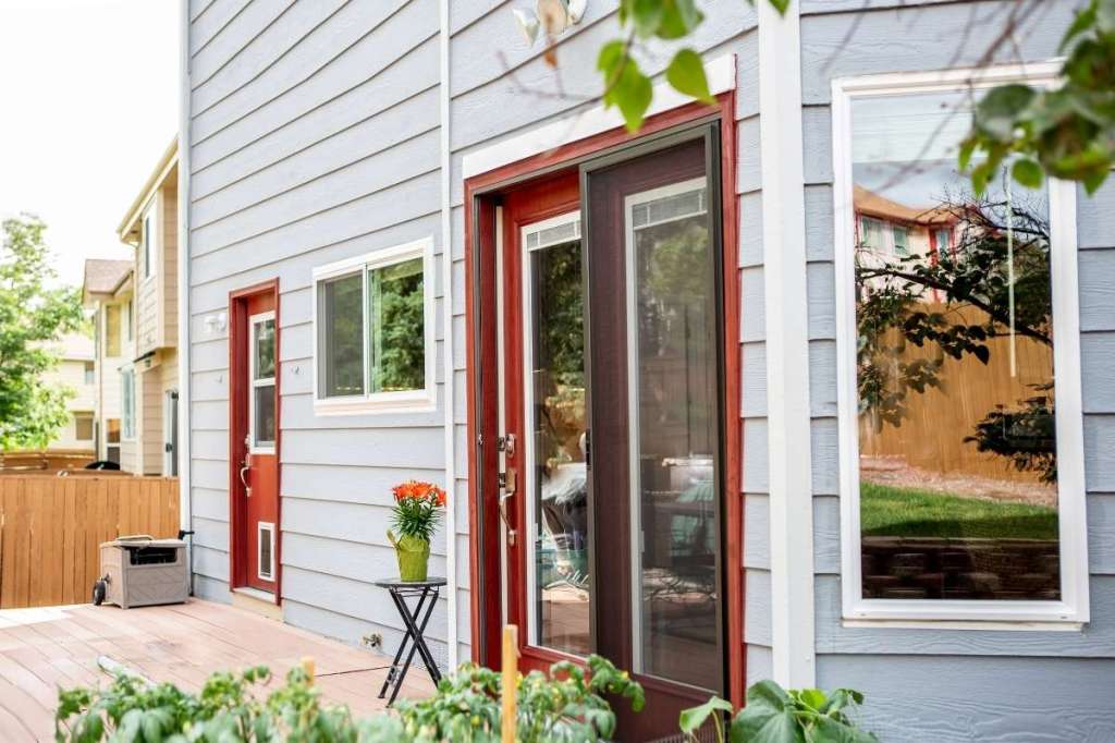 Two sets of red exterior doors on the back deck of a house.